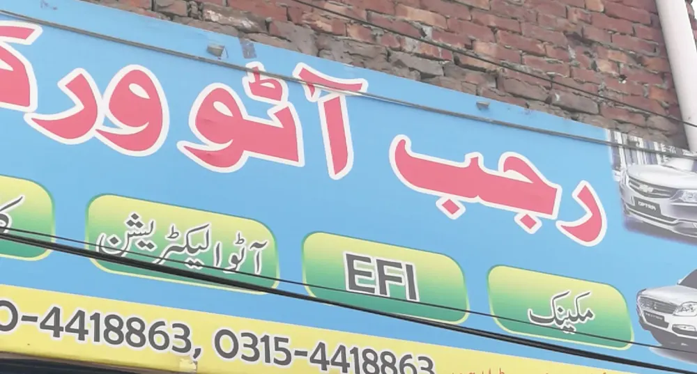 The Rajab Auto Workshop board, listing mechanic, EFI and auto electrician work